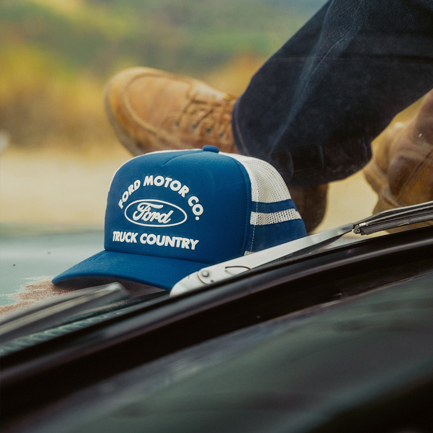 man sitting on truck with ford motor company truck hat on top