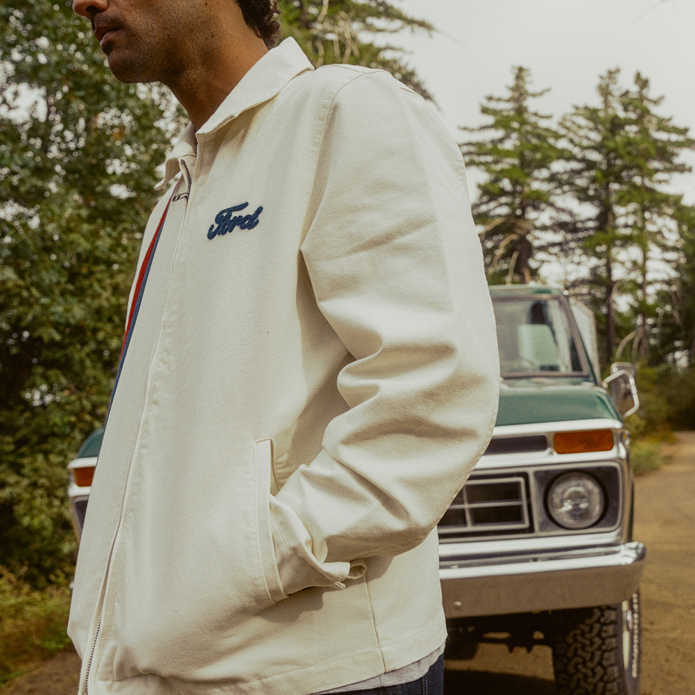 man with hand in pocket of white jacket outdoors