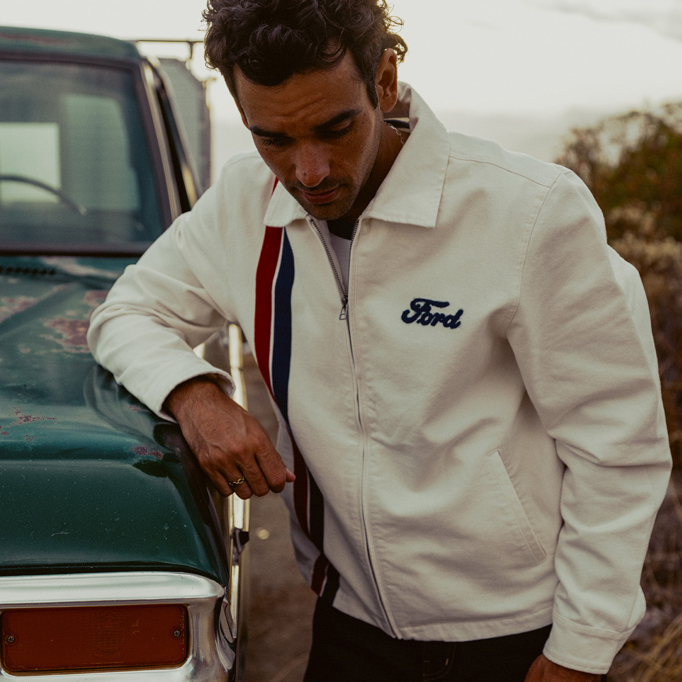 man leaning on car in white ford jacket