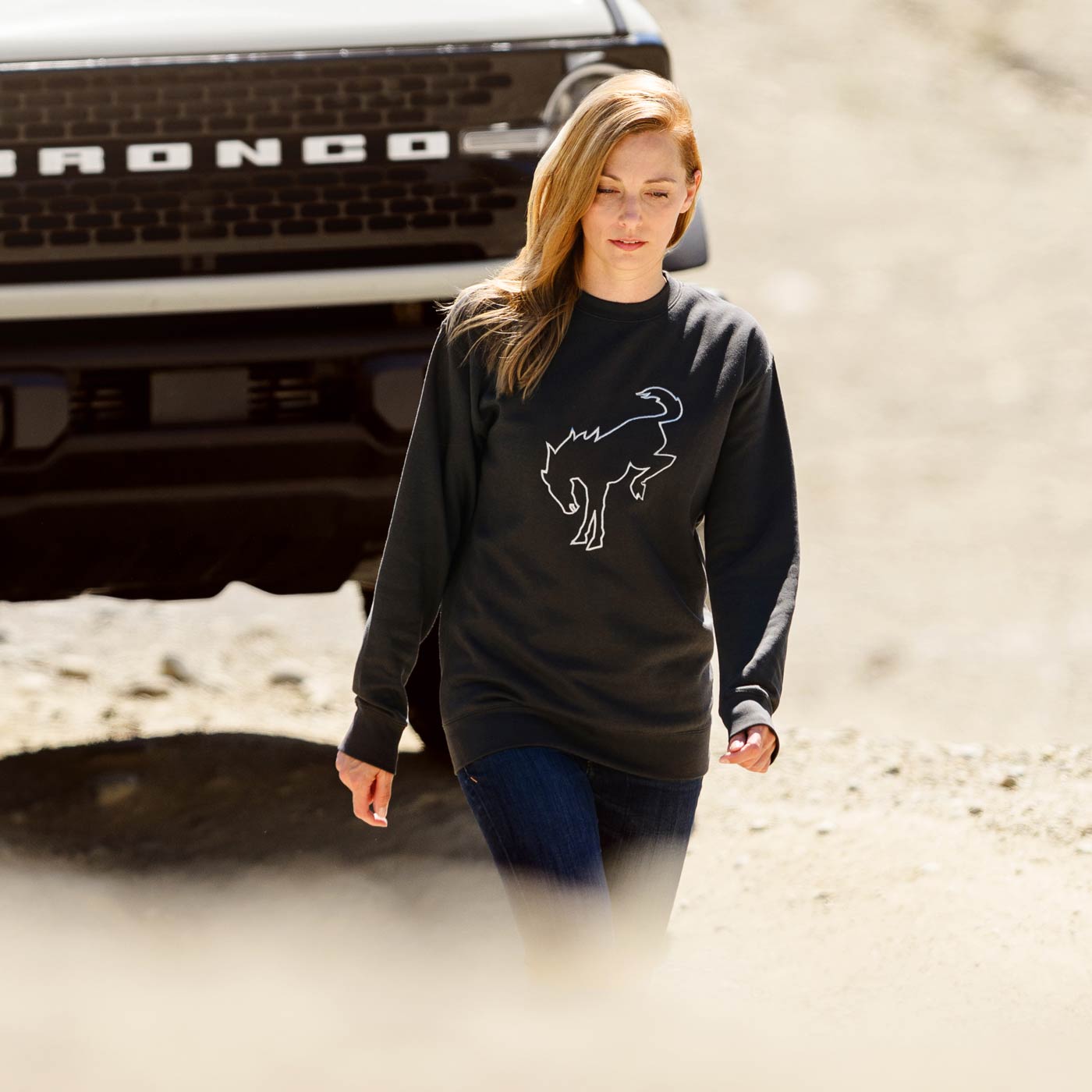 redheaded women in front of cream bronco truck wearing a charcoal gray sweatshirt with a white outlined bronco image on front