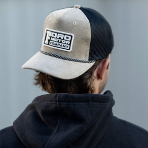 man in a corduroy Ford Motor Company beige hat with black mesh in a black hoodie