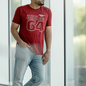 man wearing a red Mustang Since 64 t-shirt leaning on a window