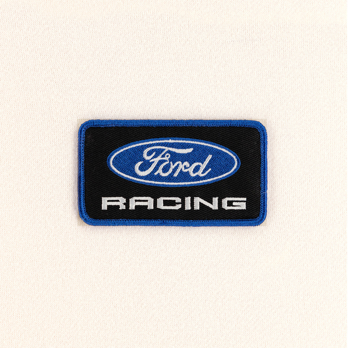 close up of a black embroidered Ford Racing patch on a cream background