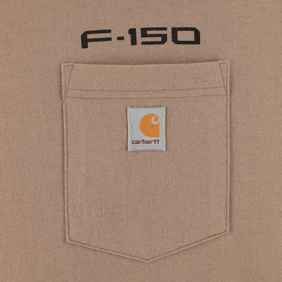 Close-up of a tan Carhartt F-150 pocket with a white Carhartt logo patch and black 'F-150' text above it.