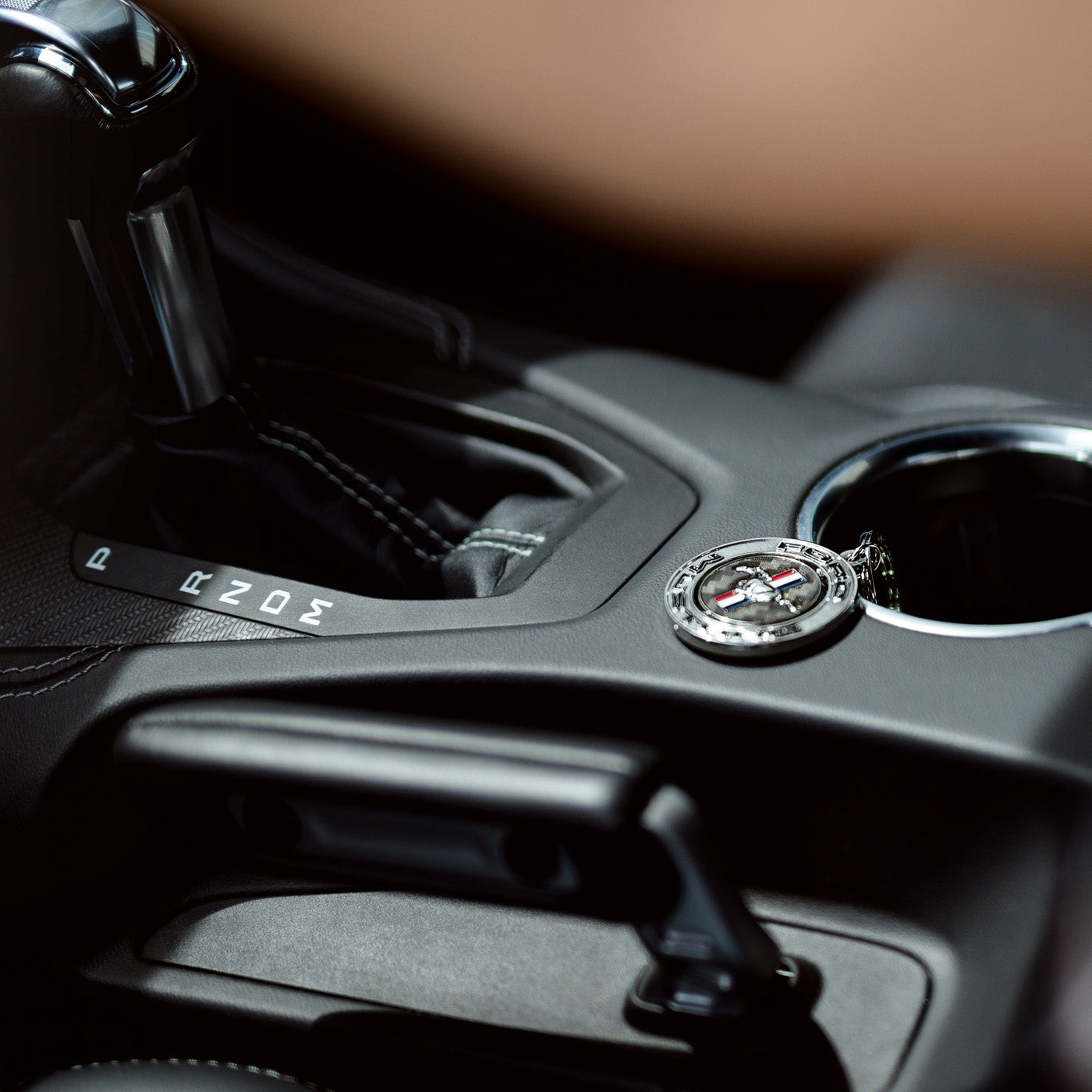 Close-up of a car's gear shift lever with a keychain attached.
