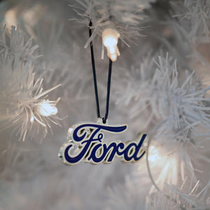 Ford logo ornament hanging on a Christmas tree with lights.