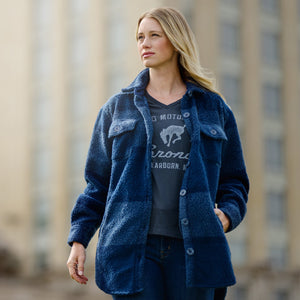 Woman wearing a blue jacket over a graphic t-shirt with a blurred cityscape background
