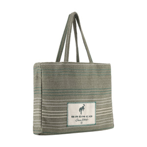 A woven tote bag in a muted sage green color with thin teal and white horizontal stripes, featuring a white rectangular patch on the front with the brand name 'BRONCO' and a horse logo.
