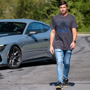 man wearing Mustang dark horse t-shirt walking in front of a mustang