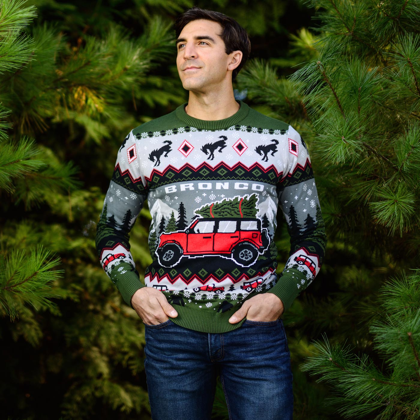 Man wearing a festive sweater with a red bronco graphic against a green leafy background