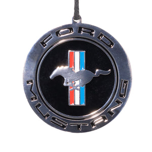 A holiday ornament featuring the Ford Mustang logo with a silver, black, red, and white enamel finish.