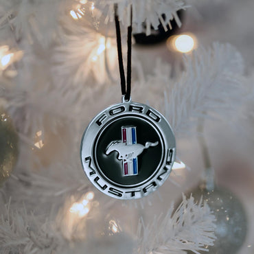 Ford Mustang logo ornament hanging on a white Christmas tree