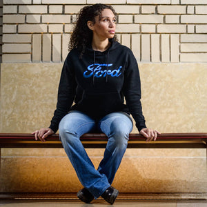 Person wearing a black hoodie with 'Ford' logo sitting on a ledge.
