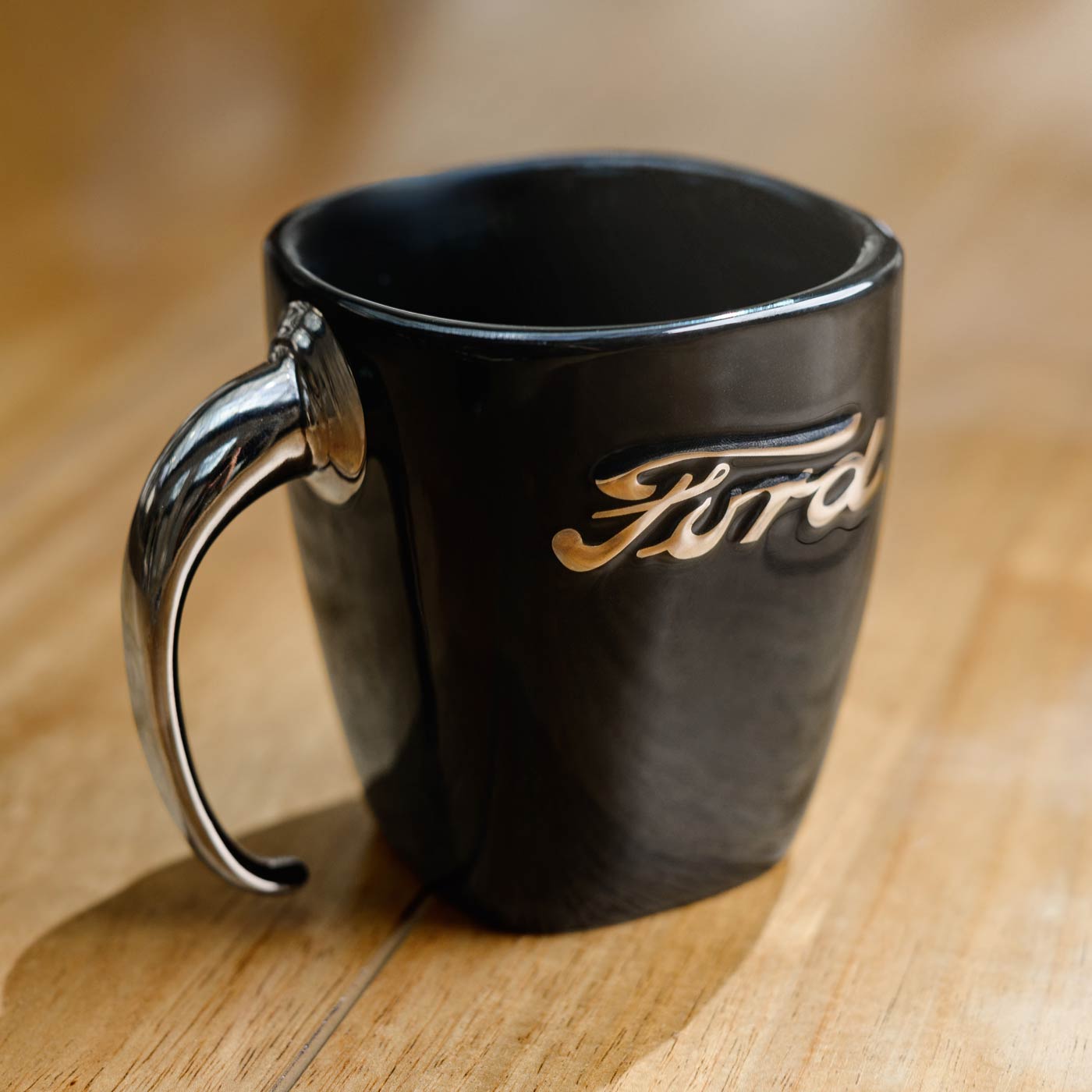 Black mug with Ford logo on a wooden surface