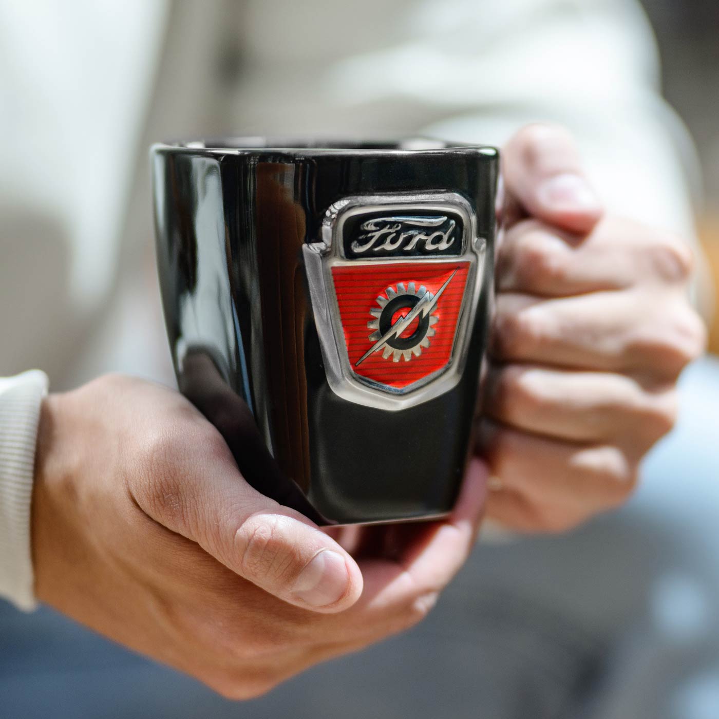 Black mug with Ford logo held by a person