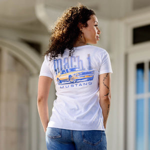Woman wearing a white t-shirt with a graphic design of a mach 1 mustang classic car and text, standing in an outdoor setting.
