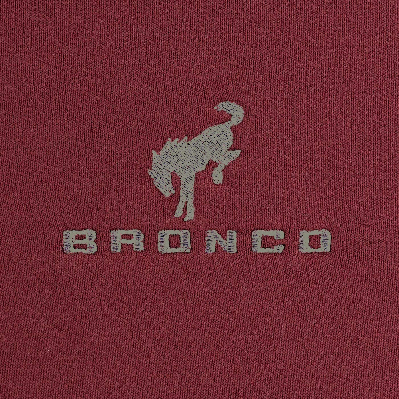 Close-up of a maroon fabric with 'Bronco' logo and horse emblem.