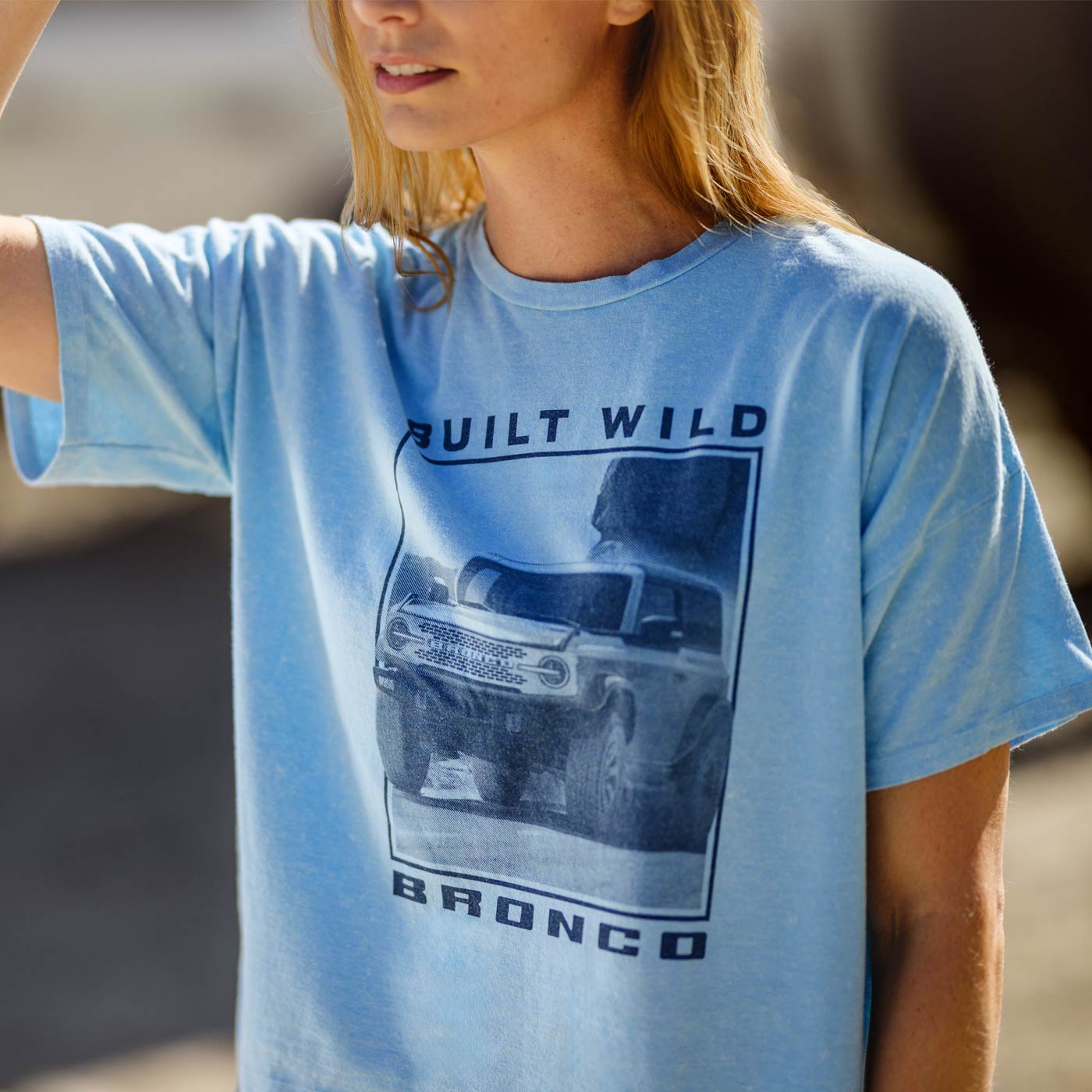 Person wearing a blue t-shirt with a graphic design and text.