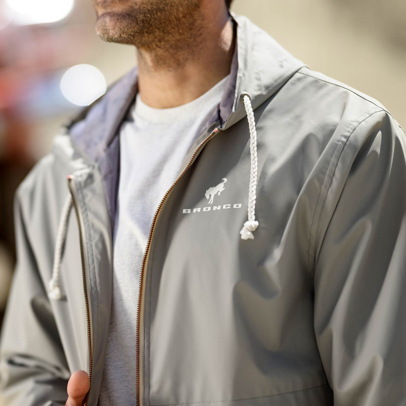 Person wearing a gray jacket with a brand logo, blurred background