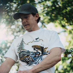 man outdoors wearing a green filson hat and graphic filson t-shirt