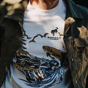 Person wearing a white t-shirt with a graphic design and 'Bronco Filson' branding.