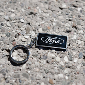 ford blue oval keychain on a pebbled background