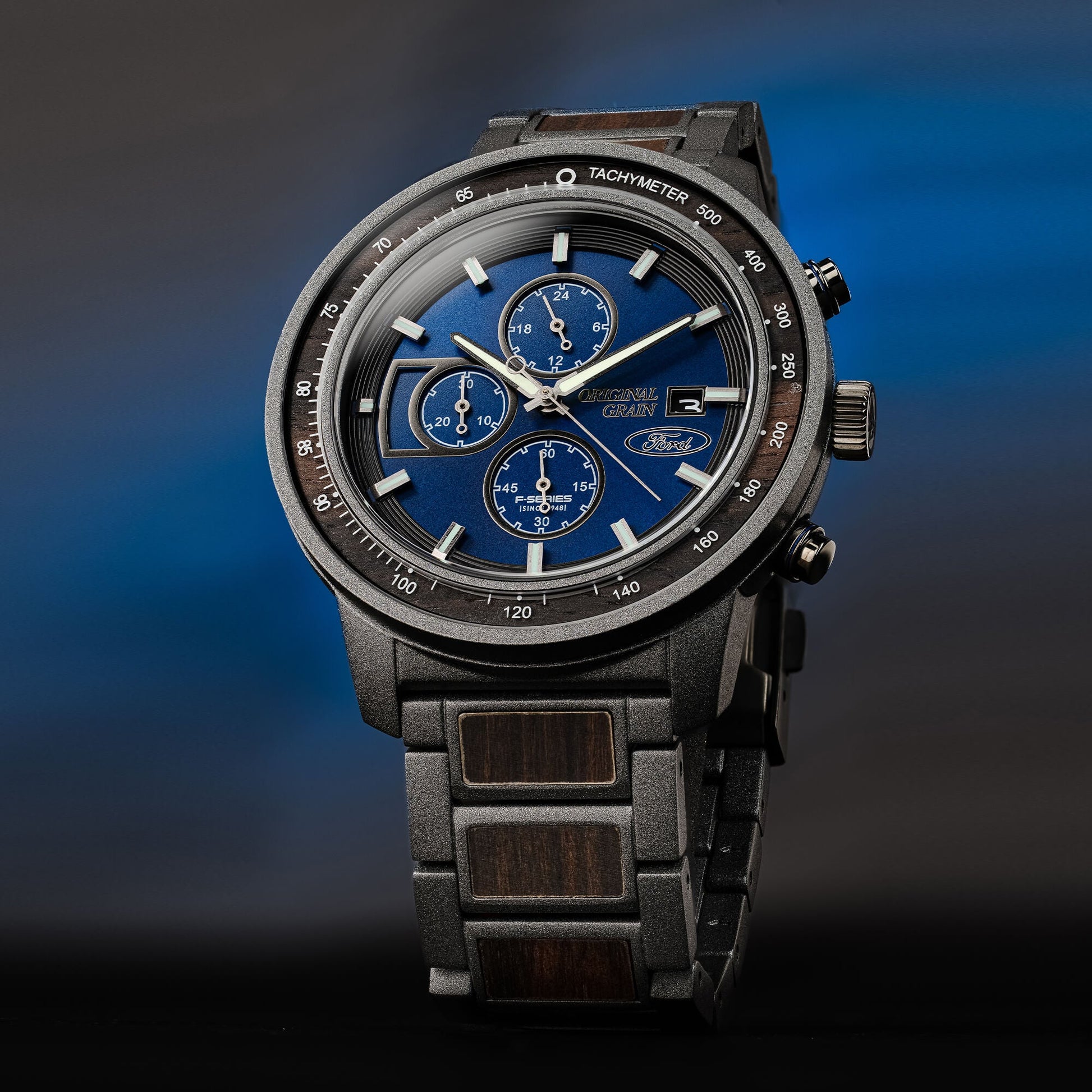 Luxury watch with blue dial and black strap on a gradient blue and black background