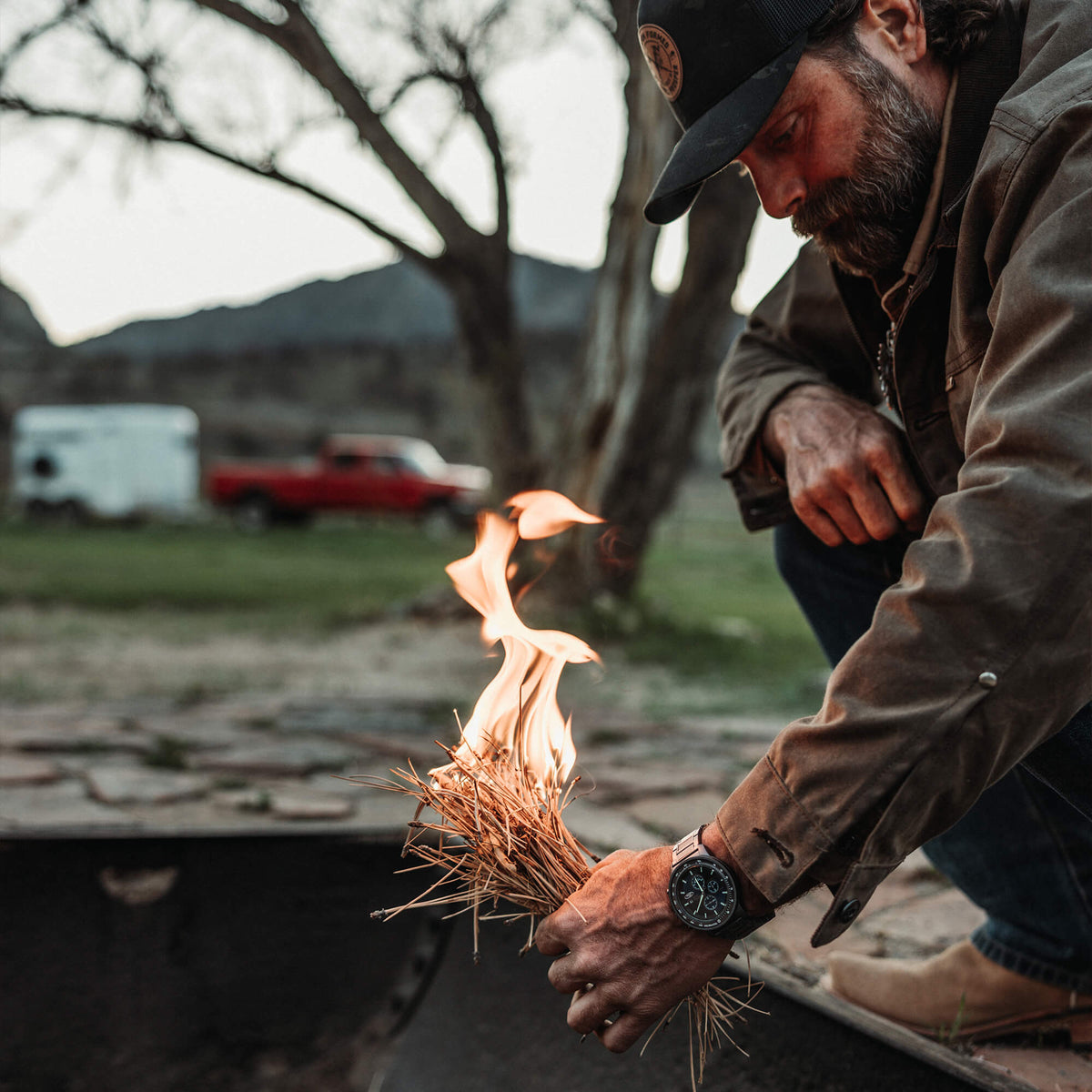 Man lighting a fire with a bundle of dry grass outdoors.