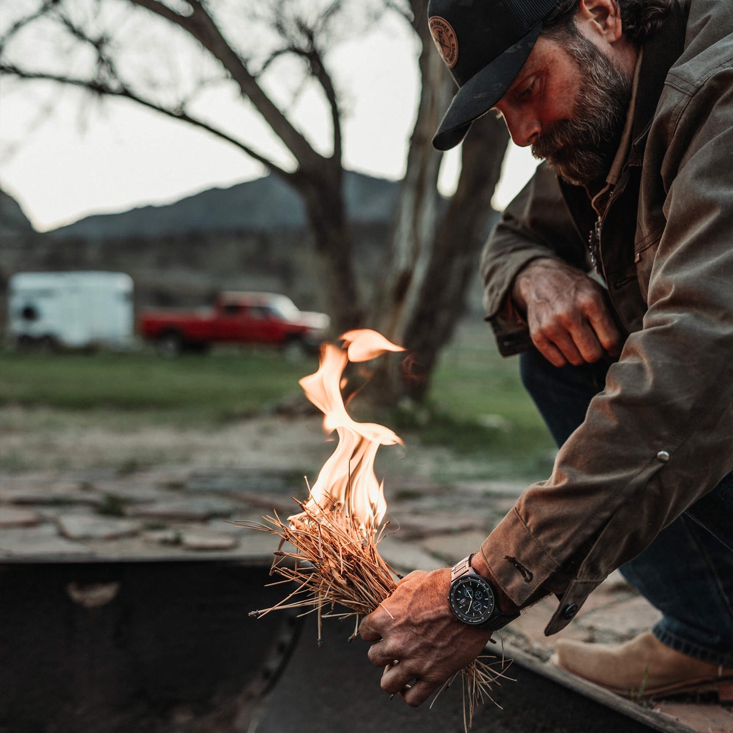 Man lighting a fire with a bundle of dry grass outdoors.