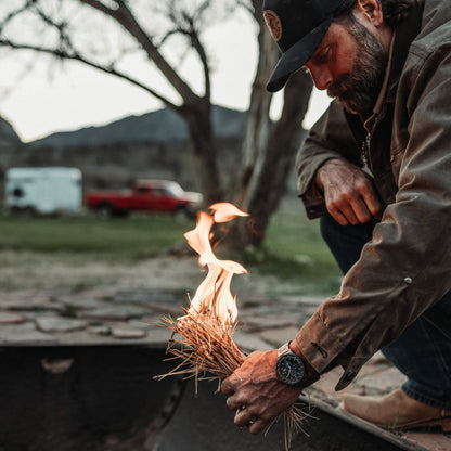 Man lighting a fire with a bundle of dry grass outdoors.