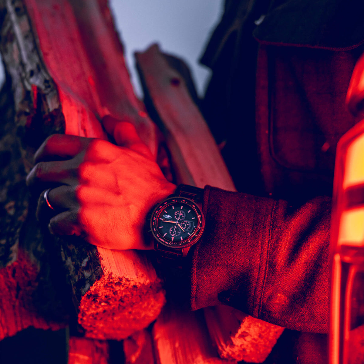 Person holding a log with a watch on their wrist, illuminated by red light