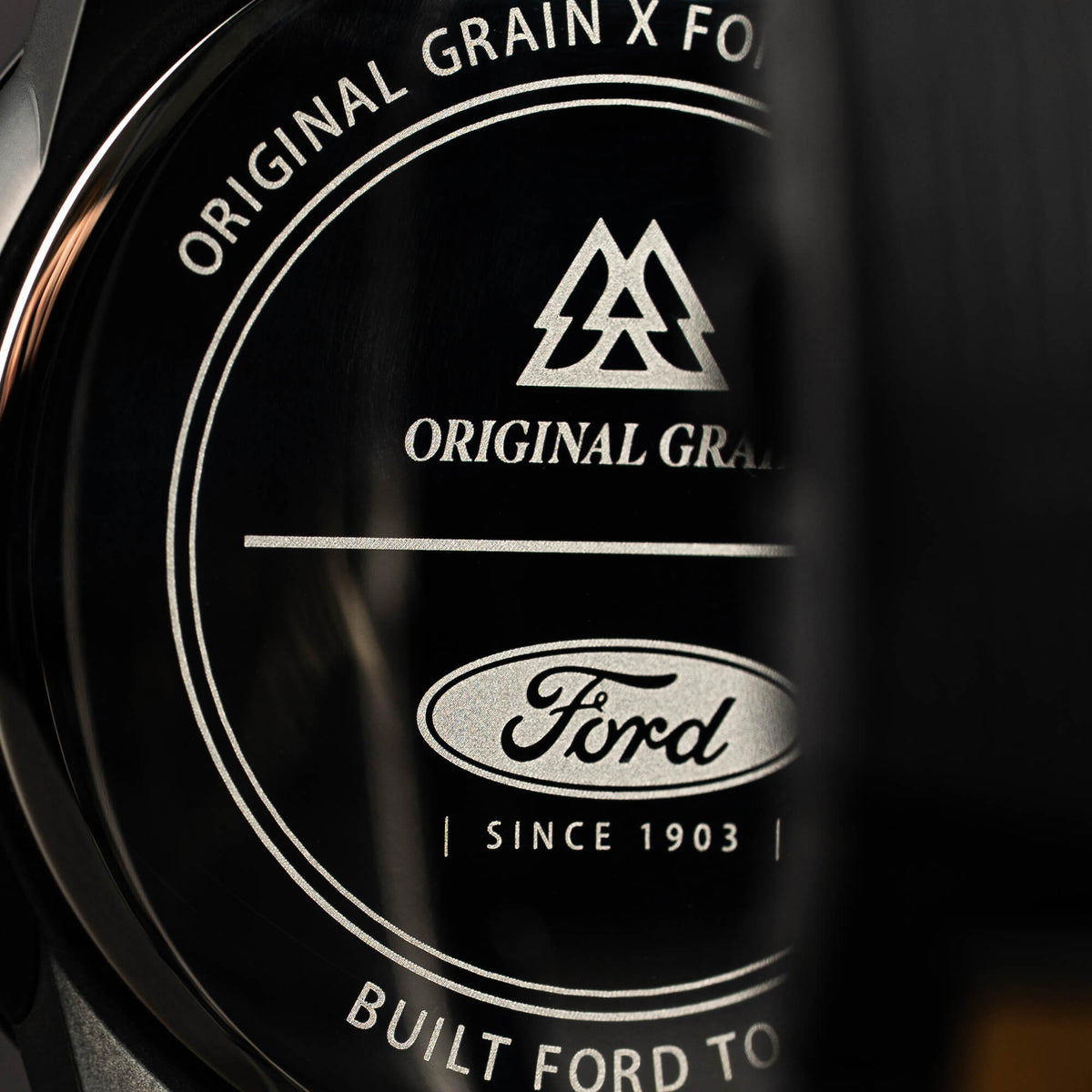 Close-up of a Ford logo with 'Original Grain' text on a dark background