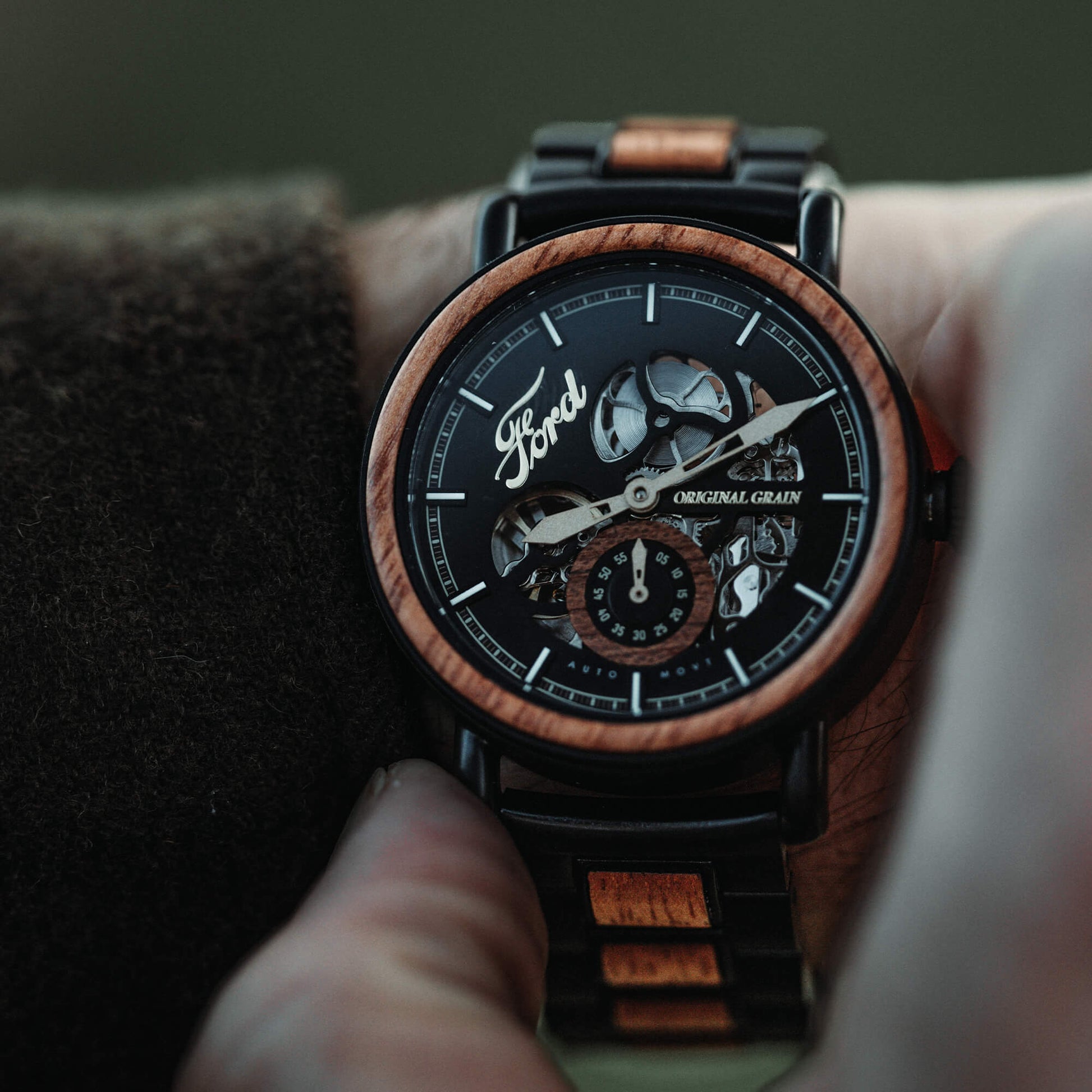 Wooden watch with black face and visible brand logo on wrist
