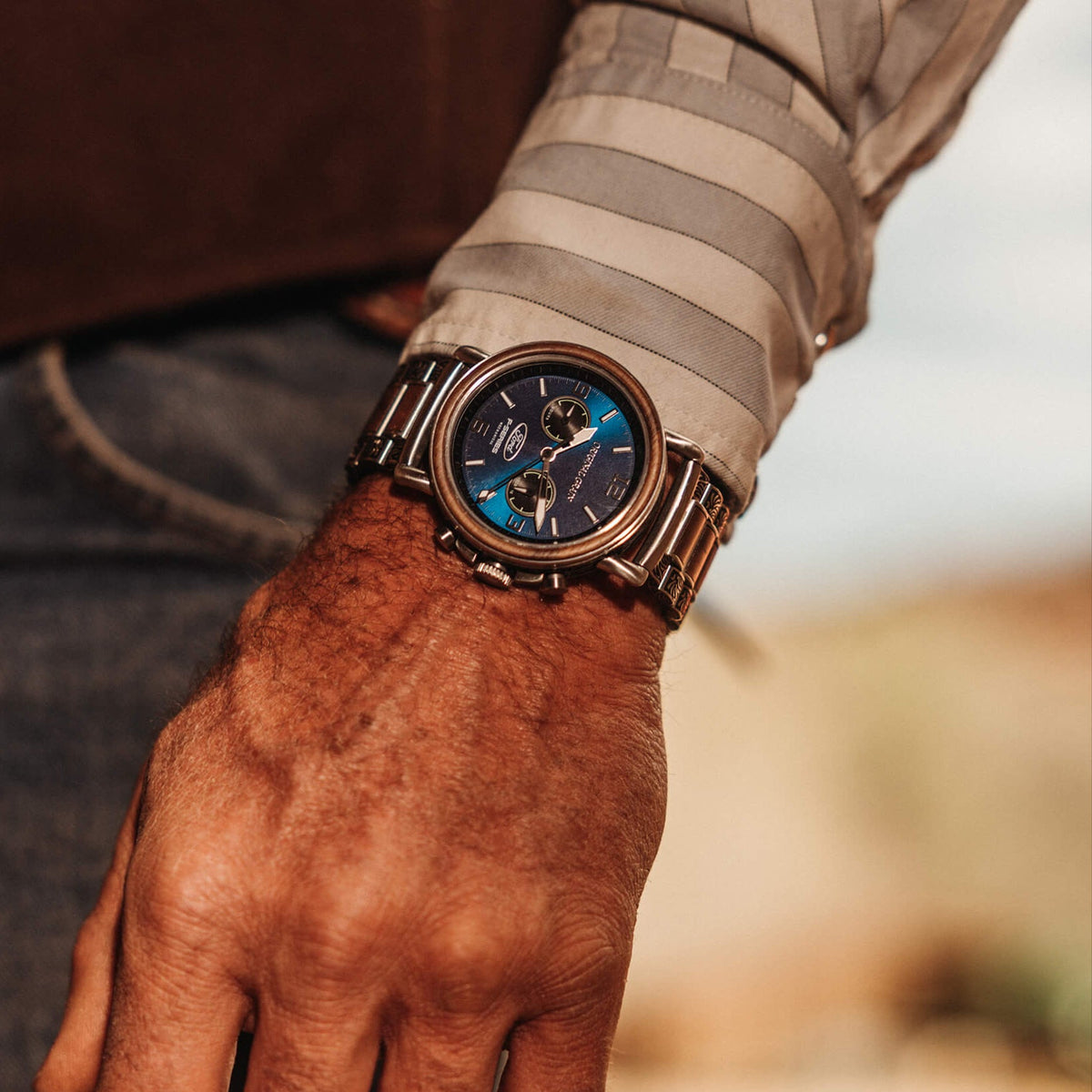 Close-up of a person's wrist wearing a detailed wristwatch with a blurred background