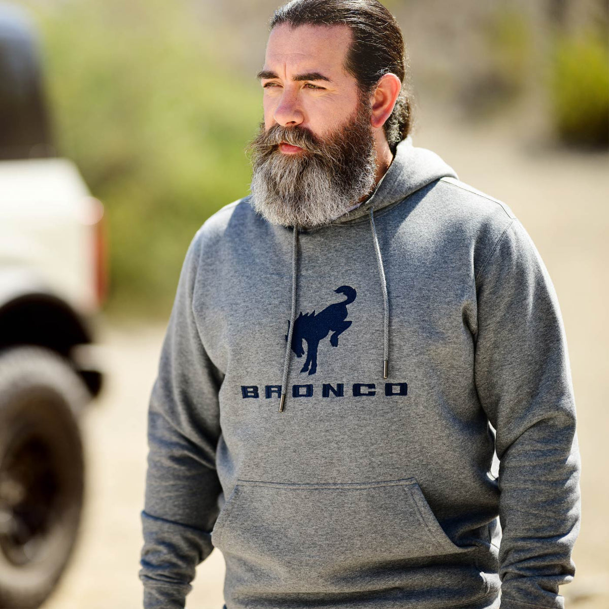 Man wearing a gray hoodie with a Bronco logo outdoors