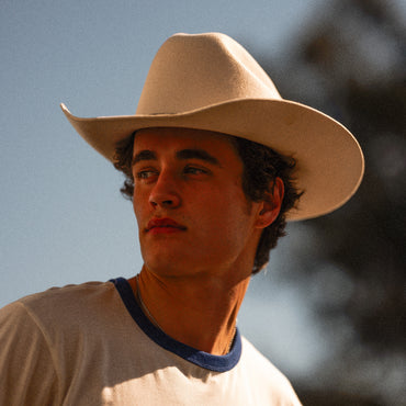 man in white cowboy hat looking off in the distance