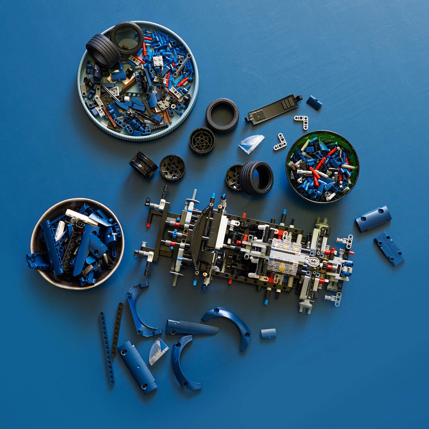 Disassembled toy car model with various parts on a blue background