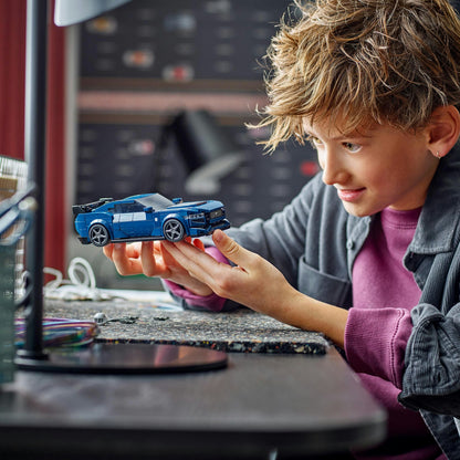 Child holding a toy car in front of a computer screen