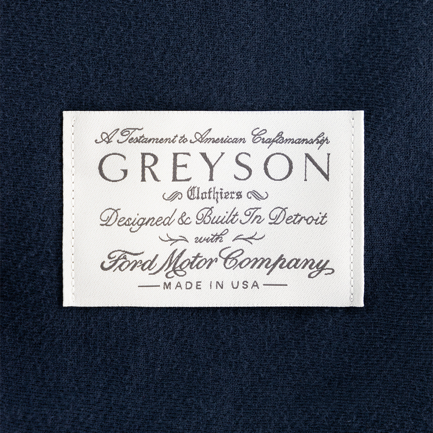 Greyson embroidered white label on a navy blue backround