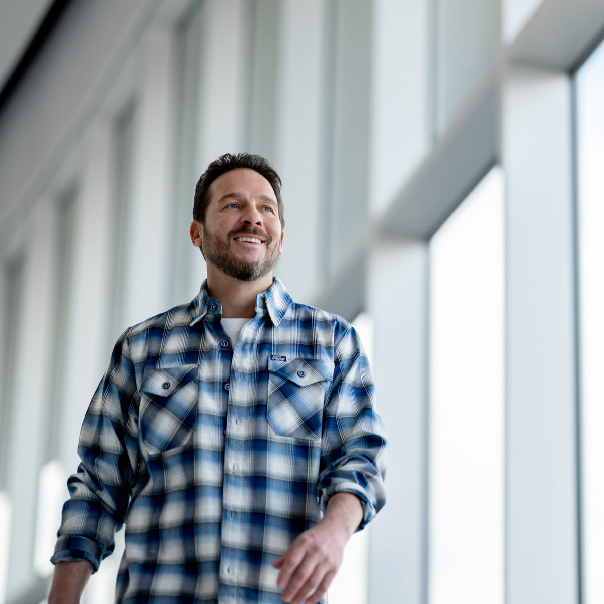 Man wearing a blue plaid ford dixxon shirt in an indoor setting