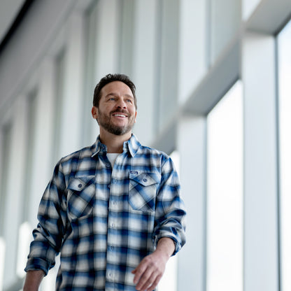 Man wearing a blue plaid ford dixxon shirt in an indoor setting