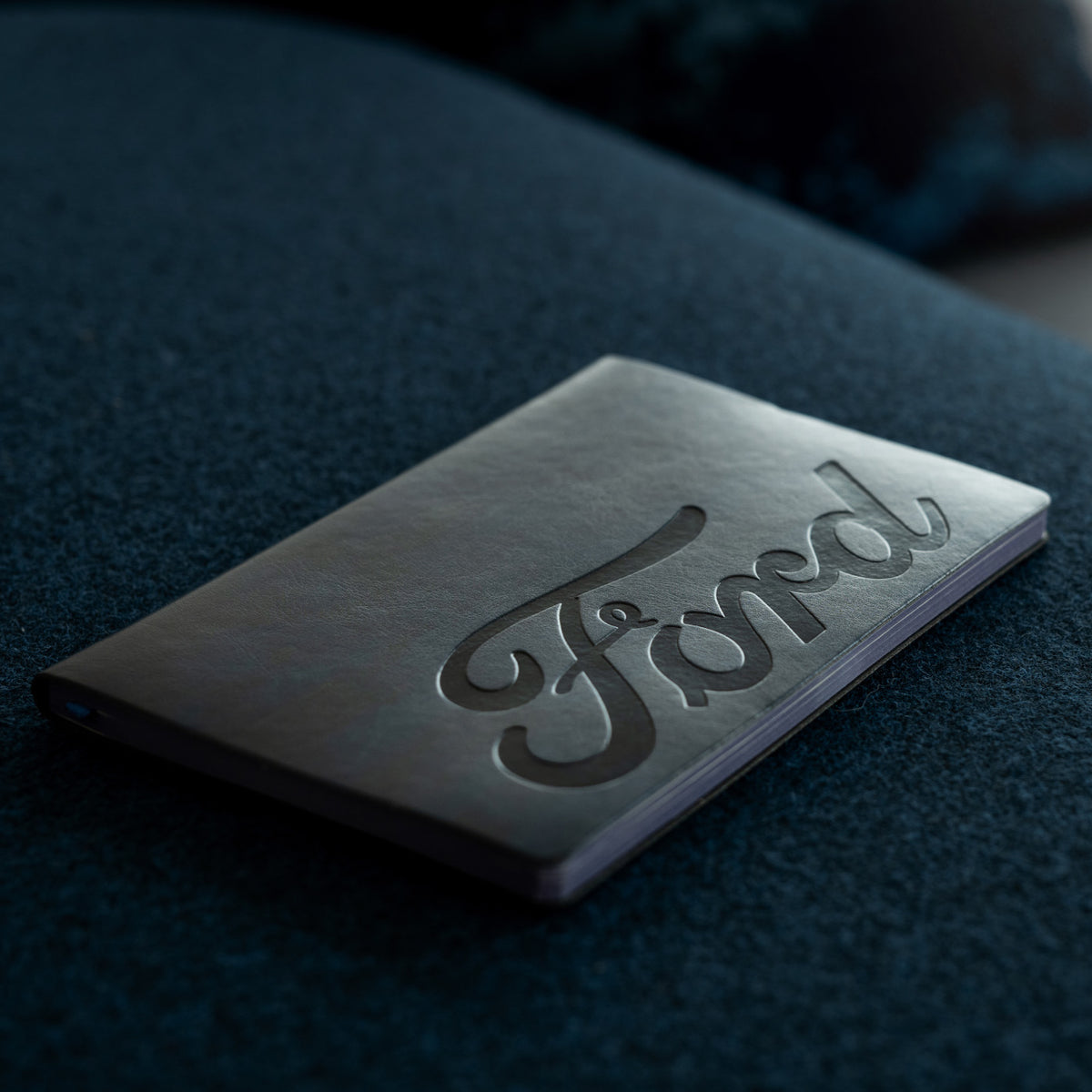 embossed Ford logo on a dark textured notebook