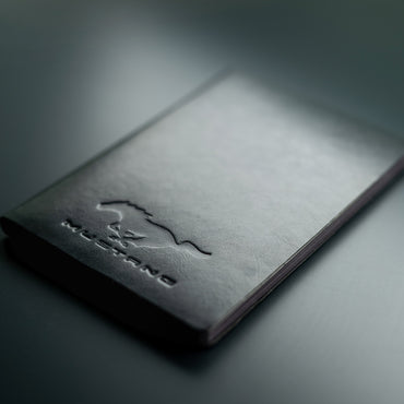 Black leather notebook with 'Mustang' embossed logo on a dark background
