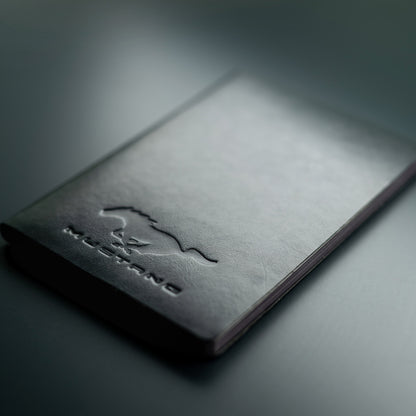 Black leather notebook with 'Mustang' embossed logo on a dark background