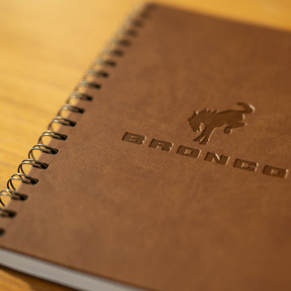 Brown notebook with 'Bronco' branding on a wooden surface