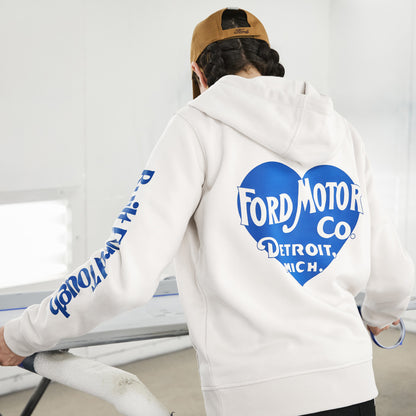 A person wearing a white hoodie with a large blue heart-shaped Ford Motor Co. graphic on the back and blue text down one sleeve, photographed from behind in a bright indoor setting.