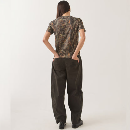 A woman shown from the back wearing a short-sleeve camouflage-patterned top and dark wide-leg pants against a plain light background.