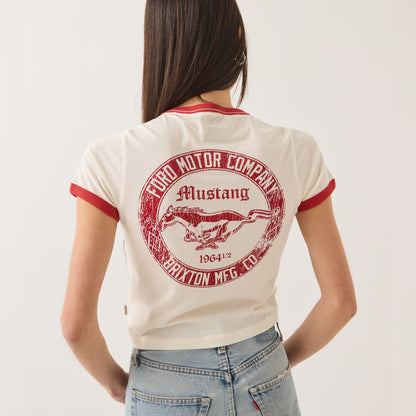 A woman shown from the back wearing a cream ringer t-shirt with red trim and a large red circular 'Ford Motor Company Mustang' graphic on the back, paired with light blue jeans against a plain white background.