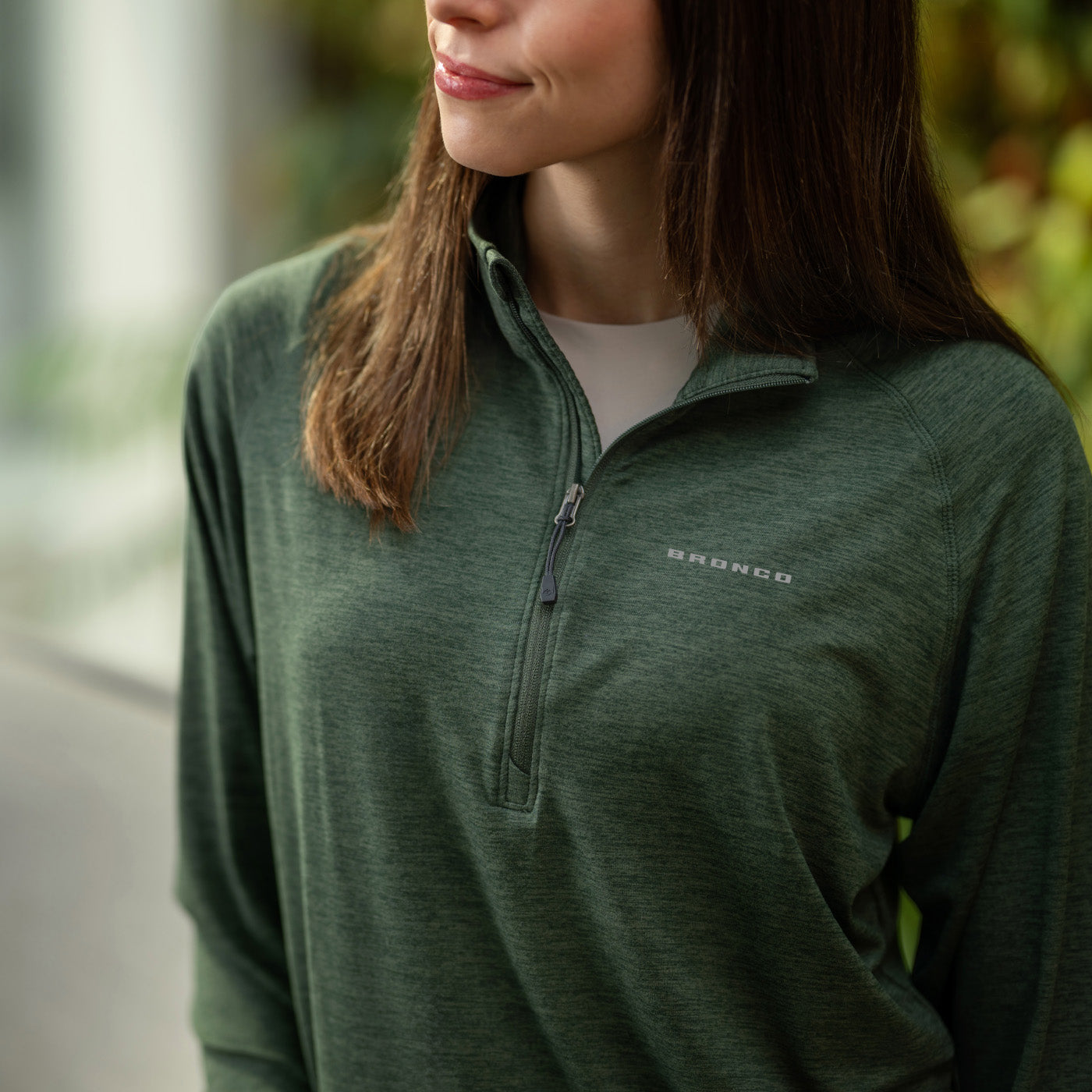 Person wearing a green half-zip pullover with 'Bronco' branding.