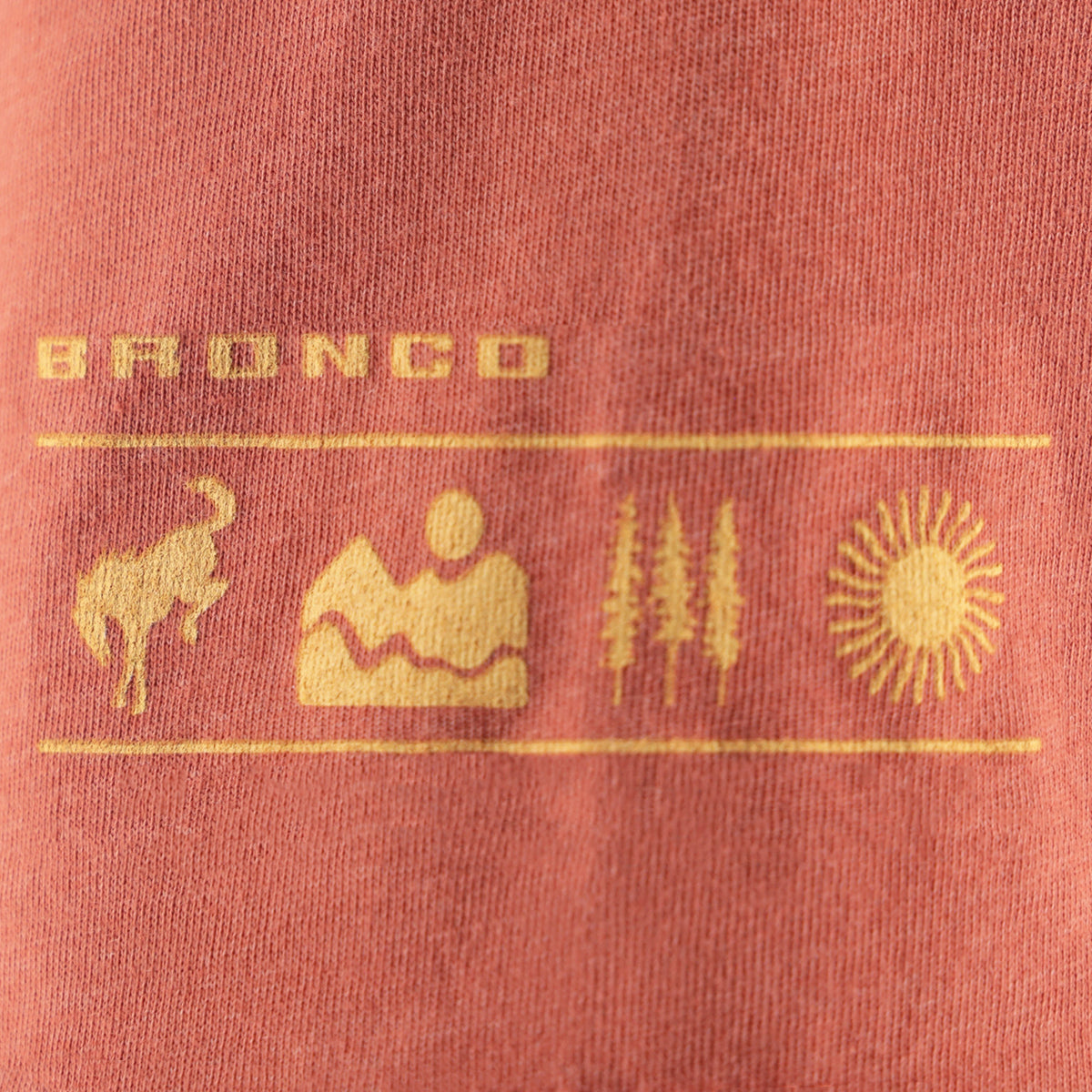 Close-up of a red fabric with 'Bronco' branding and symbols in gold.